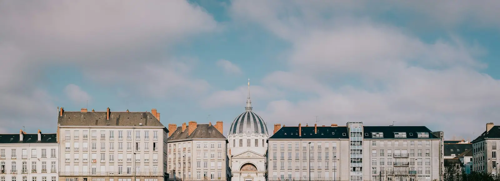 Façades de quai et dôme d’église de Nantes sous un ciel nuageux, vue panoramique
