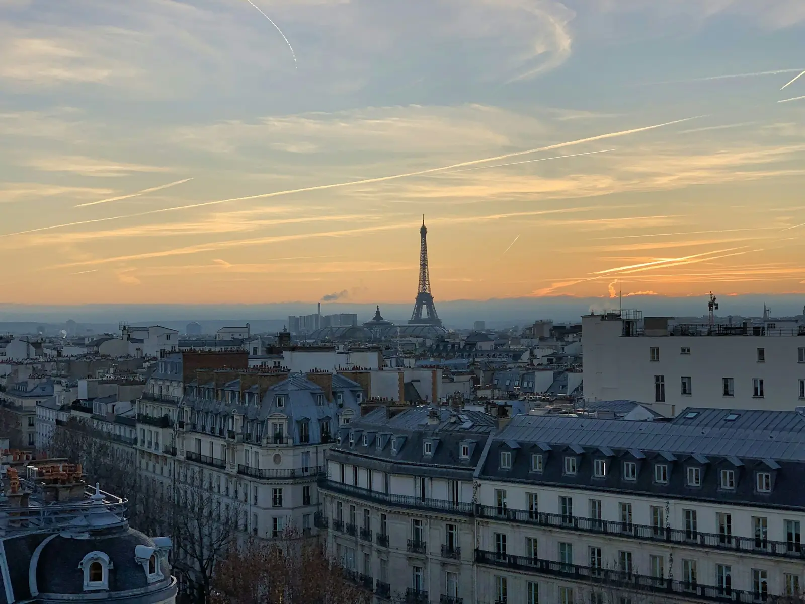 Toits haussmanniens de Paris au coucher du soleil, tour Eiffel à l’horizon
